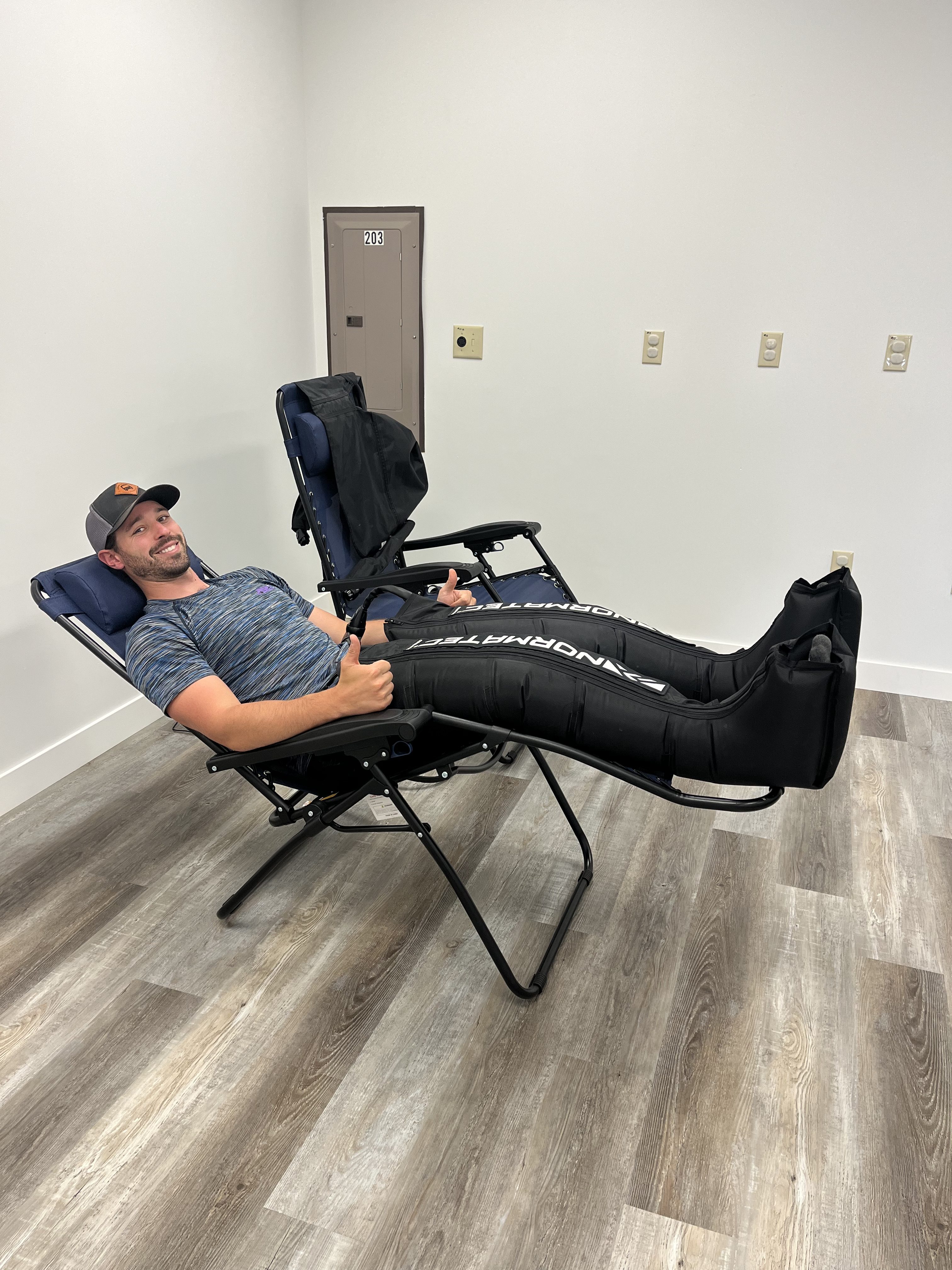 Man sitting in a chair using the normatec sleeves to help recover from a thigh contusion.